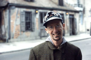 A man in a hat standing on a street.