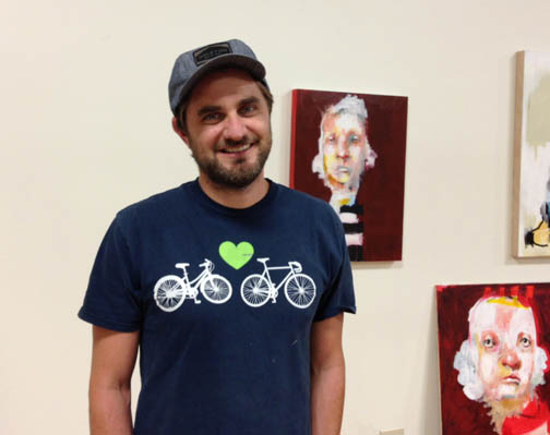 Spencer Herr standing in front of his paintings.