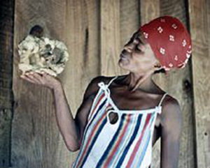 A woman holding a rock in front of a wooden house.