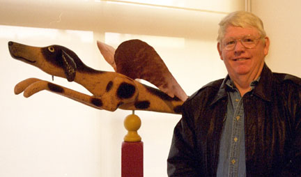 A man standing next to a wooden sculpture of a dog.