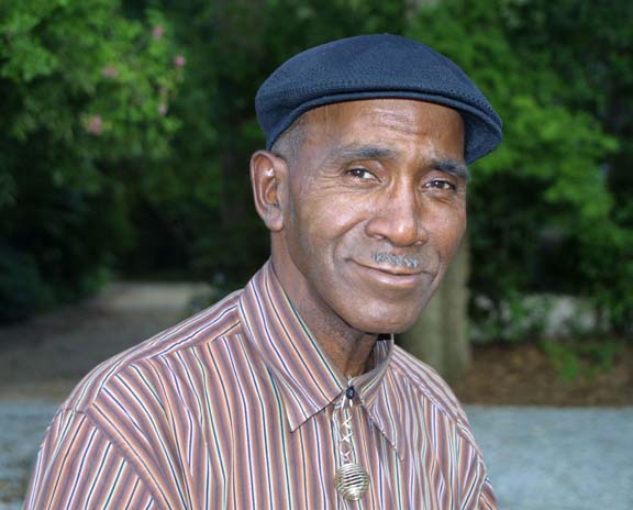 An older man wearing a striped shirt and hat.