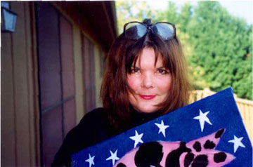 A woman holding a painting of a cat with stars on it.