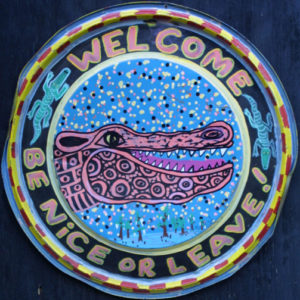A welcome sign with a crocodile on it.