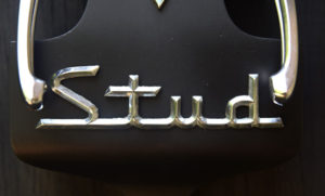 "Stud" Wall Clock  by Jason Burnett  wood, found objects: salvaged window retractors, trophy parts, Studebaker emblem  15.25" x 5.75" x 3"   $300  #12088