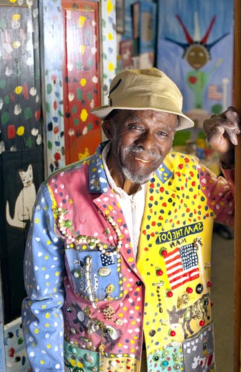 A man in a colorful jacket standing in front of a door.