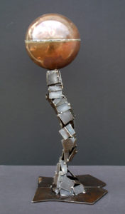 A small metal sculpture of a human with big head and feet