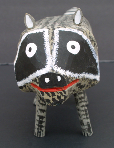 A raccoon made of clay with eyes and a nose.