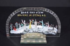 "Book End View" #1384 c. 1977 by Howard Finster Provenance: Marshall Hahn pain on glass 6" x 10.5" x 2.5" $1800 #13409